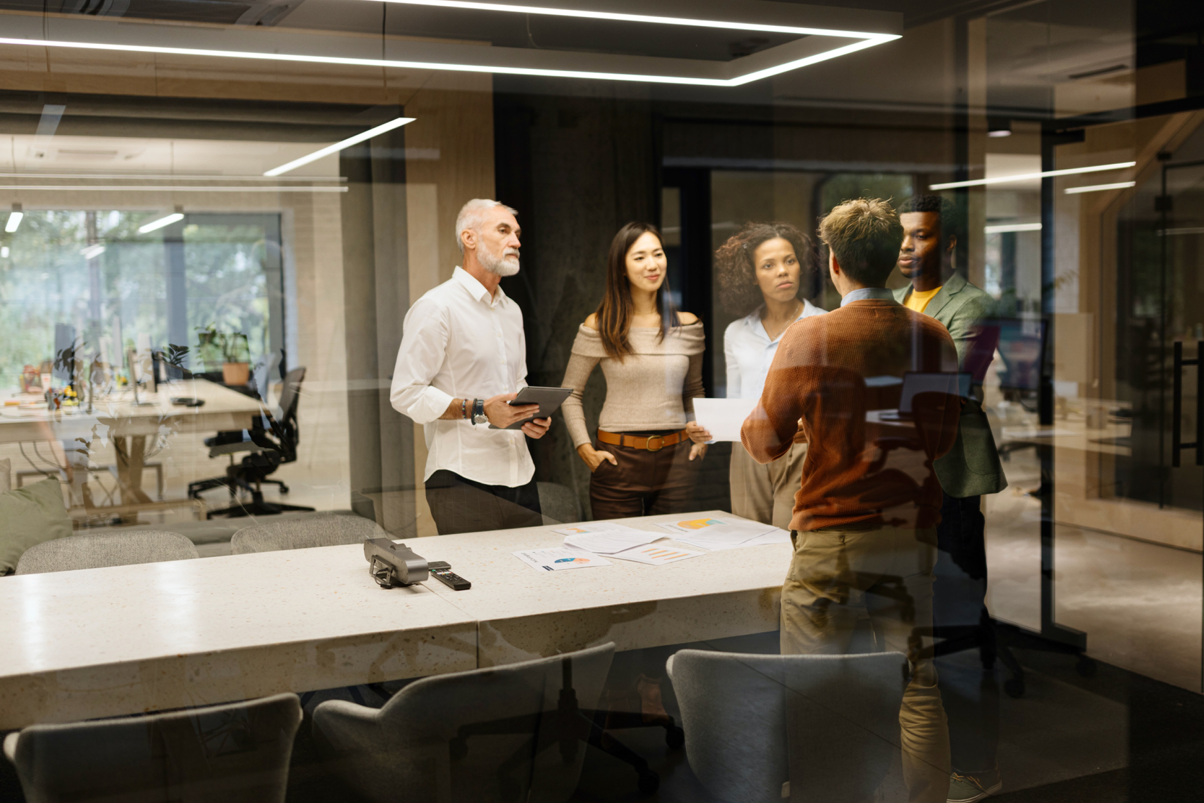 A group of colleagues discussing a project around a table in a modern office.
