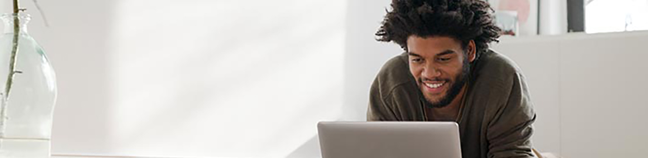 Man sitting in office looking at laptop and smiling