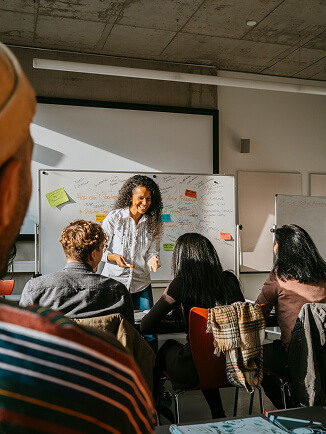 An instructor presenting a lesson to students in a classroom with a whiteboard.